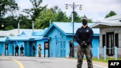 FILE - South Korean soldier (R) and United Nations Command soldier (background, in green) stand guard near the military demarcation line separating North and South, at the Joint Security Area of DMZ in the truce village of Panmunjom, Oct. 4, 2022.