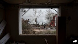 Firefighters are seen through a destroyed apartment window as they work to extinguish a fire after a Russian attack in Kharkiv, Ukraine.