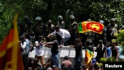 Demonstrators stand on the wall of Sri Lanka's Prime Minister Ranil Wickremesinghe's office premises, amid the country's economic crisis, during a protest in Colombo, Sri Lanka July 13, 2022. (REUTERS/Adnan Abidi)