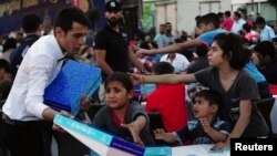 Ramazan'da kurulan iftar sofralarında dağıtılan yiyecek kutularından almak için çabalayan Suriyeli çocuklar