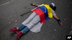 Một người biểu tình quấn cờ Venezuela quanh mình, nằm bên ngoài phái bộ ngoại giao của Vatican tại Caracas, Venezuela. 