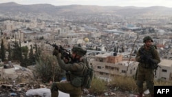 TOPSHOT - An Israeli soldier aims his rifle during a raid at the Balata camp for Palestinian refugees, east of Nablus in the occupied West Bank on November 19, 2023, amid the ongoing battles between Israel and the Palestinian militant group Hamas. (Photo 